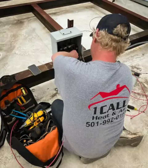 An AC technician from One Call Heat & Air works diligently to install wiring for an AC repair.