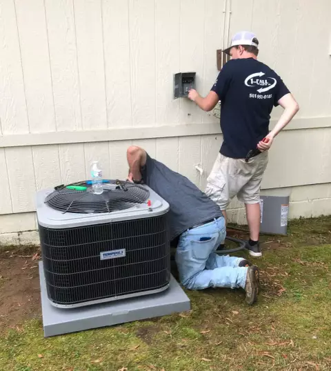 Two technicians working on a Tempstar HVAC unit