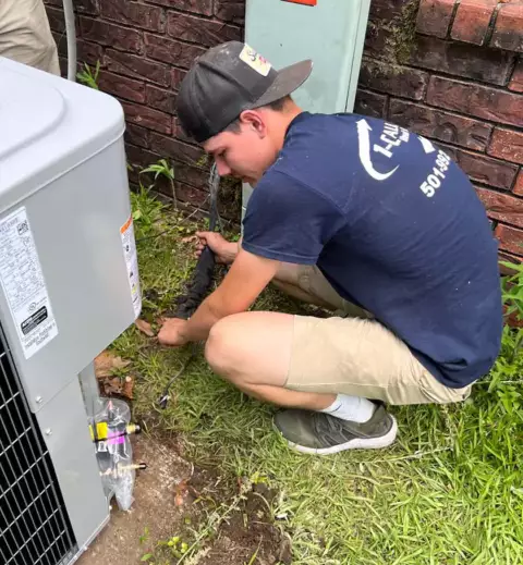 An AC technician from One Call Heat & Air works diligently to repair a customer's air conditioning unit.